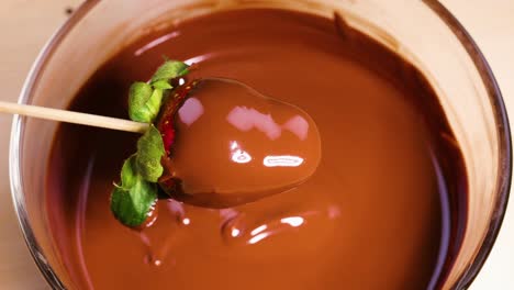 strawberry being dipped into melted chocolate