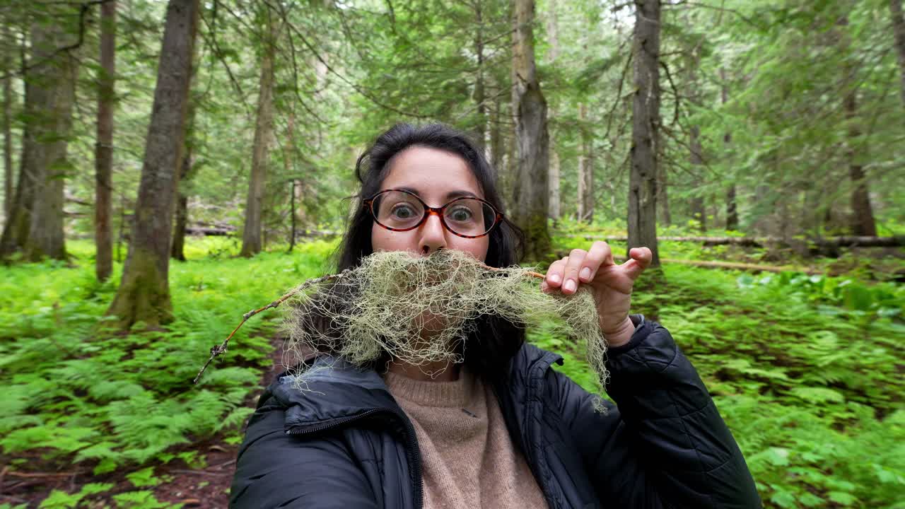 Nainen tekee hauskan viiksen luppojäkälästä metsäretken aikana.