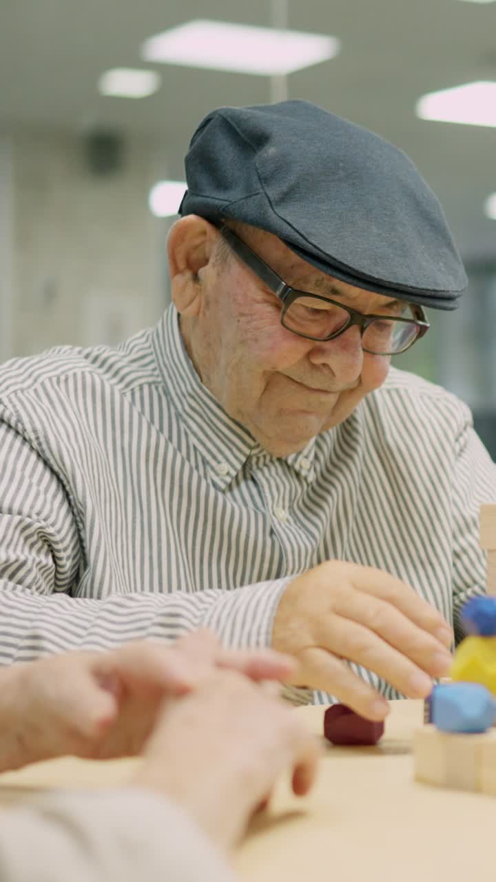 Elderly man playing with wooden blocks for cognitive therapy