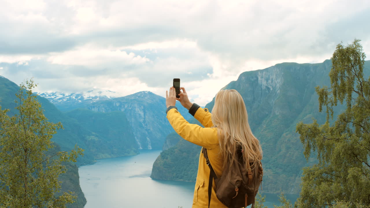 mujer tomando una foto del fiordo noruego