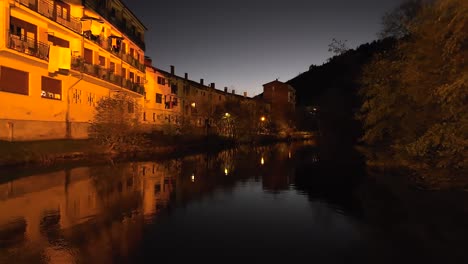 drone flying backward and below medieval stone bridge in balmaseda during nighttime , spain