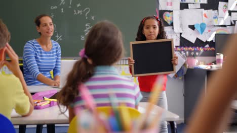 Vista-Frontal-De-Una-Colegiala-Afroamericana-Explicando-Sobre-La-Pizarra-En-El-Aula-4k