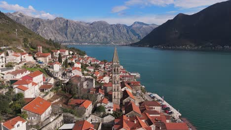 Imágenes-De-Drones-En-4k-Capturan-La-Iglesia-De-San-Nicolás-En-La-Encantadora-Ciudad-De-Perast,-Montenegro,-Con-Una-Hermosa-Vista-De-La-Bahía-Turquesa-De-Kotor,-Declarada-Patrimonio-De-La-Humanidad-Por-La-Unesco,-Y-Las-Montañas-Al-Fondo.