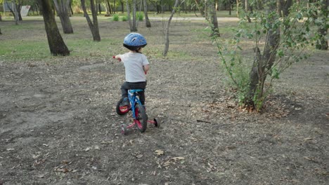 a boy on his bike in a park with many trees