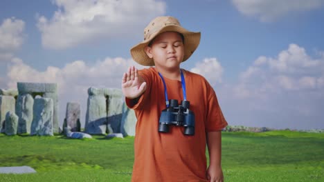 asian boy with a hat and binoculars shaking head waving hand showing no gesture avoid offer while traveling in stonehenge. boy researcher, travel tourism adventure concept