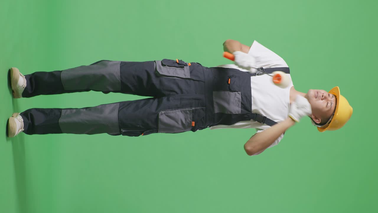 Full Body Of Asian Man Painter Wearing Safety Helmet Dancing While Standing In The Green Screen Background Studio