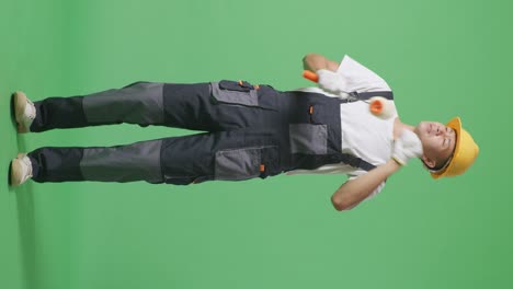 full body of asian man painter wearing safety helmet dancing while standing in the green screen background studio