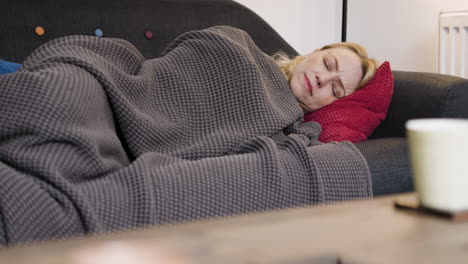 woman sleeping on a couch under a blanket