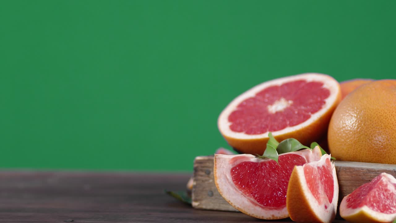 Pieces of fresh grapefruit on wooden tray is slowly rotating.