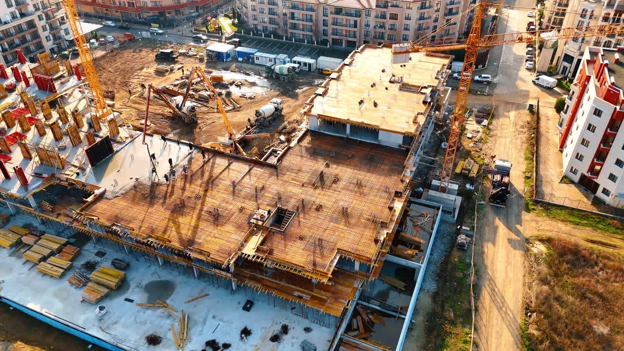 Top down view of building roof construction and equipment. Aerial shot of concrete pump and workers on building frame