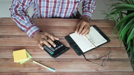 person using calculator and notebook at a desk