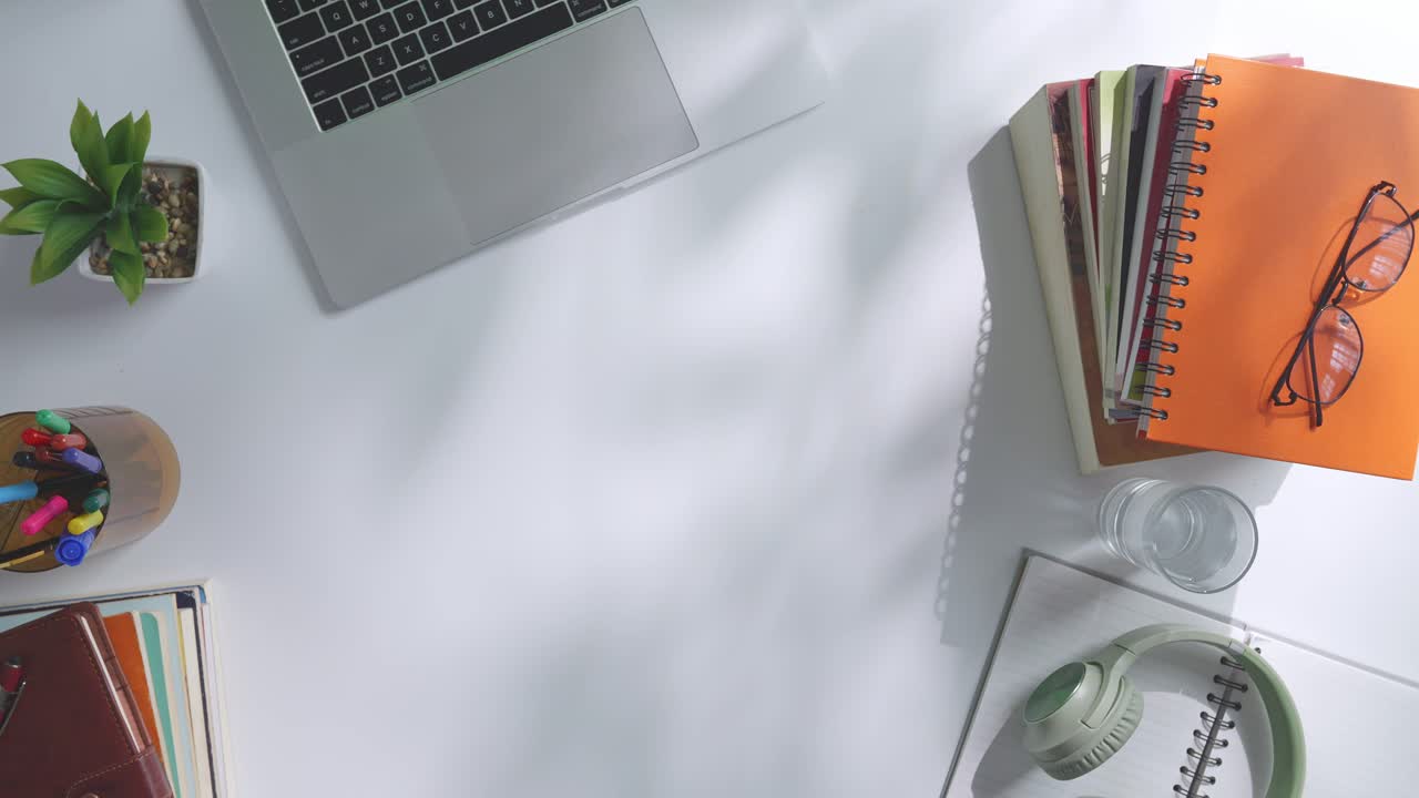 초록색 화면을 모방한 노트북 컴퓨터의 상단에서 아래로 볼 때, 펜, 안경, 그리고 물 한 잔을 가진 노트북 에 나무 사무실 책상 위에 크로마키 디스플레이가 있습니다.