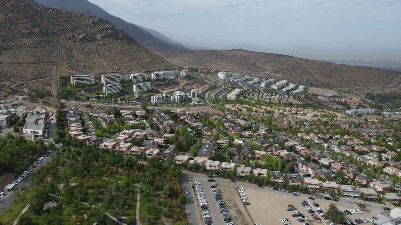 Urban sprawl extends into the valley, showcasing a mix of residential homes and apartment buildings against a mountainous backdrop