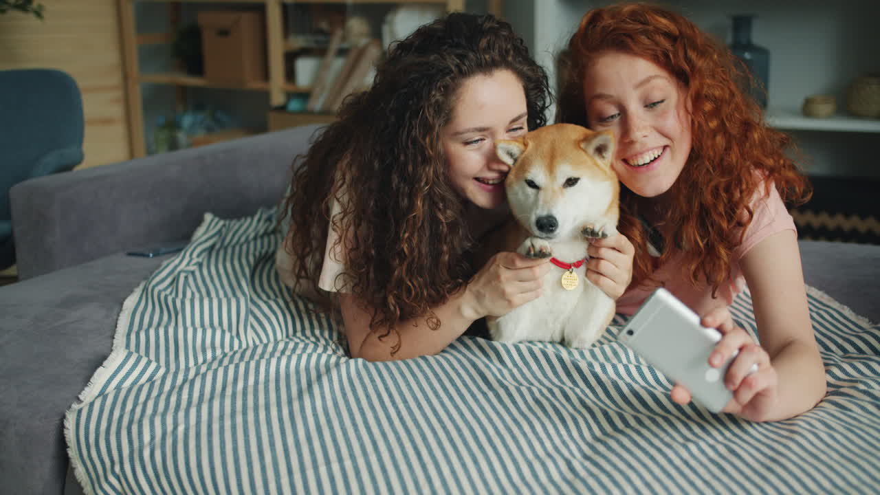 Two girls taking a selfie with their dog
