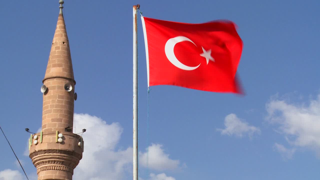 una bandera turca ondea cerca de una mezquita