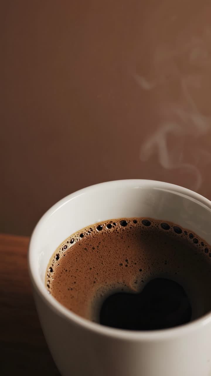 Fotograma de primer plano de un vídeo de una taza de café humeante desde un ángulo alto, capturando la rica textura