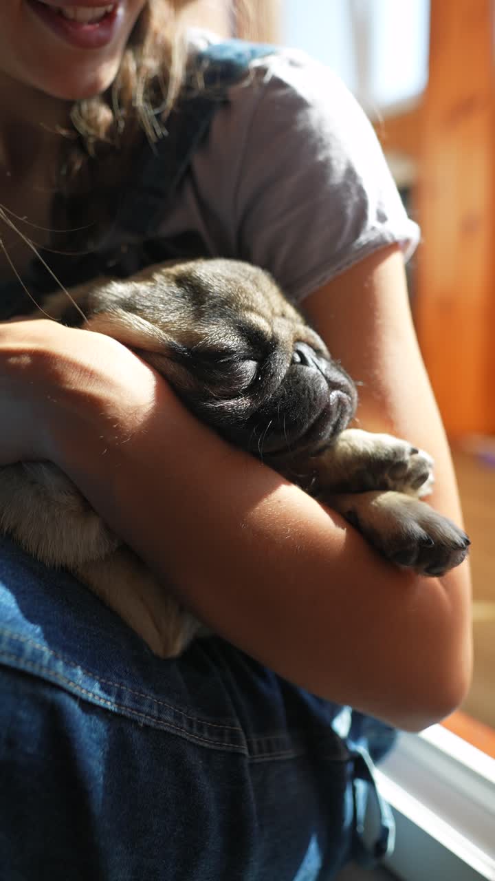 una chica abrazando a un cachorro pug dormido