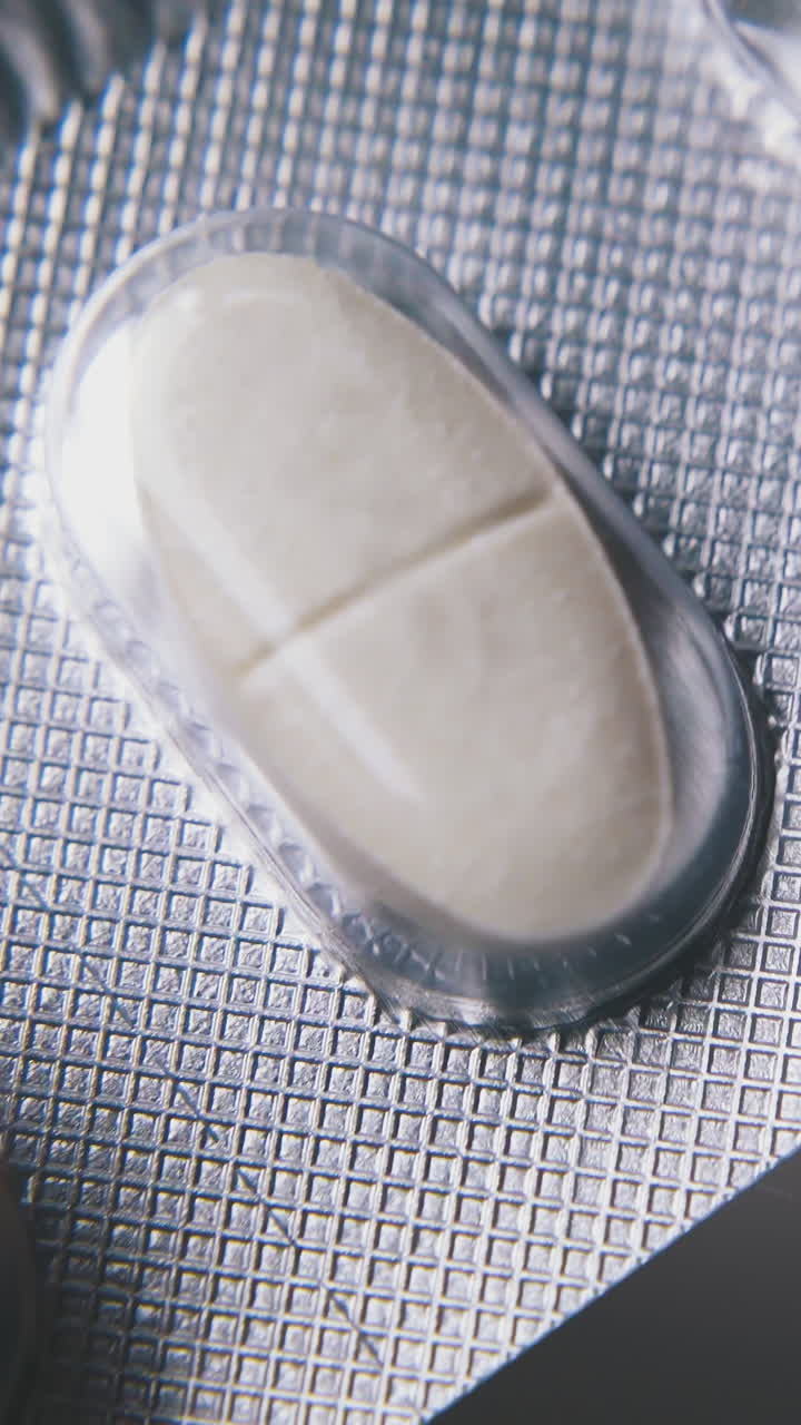 man examines silver blister with white medical pills holding in hands drugs on light background extreme close view
