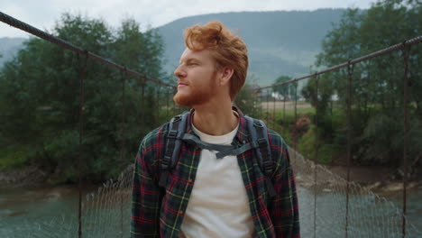 un excursionista caminando por el puente de mountain valley. un tipo pelirrojo disfrutando de la aventura afuera.