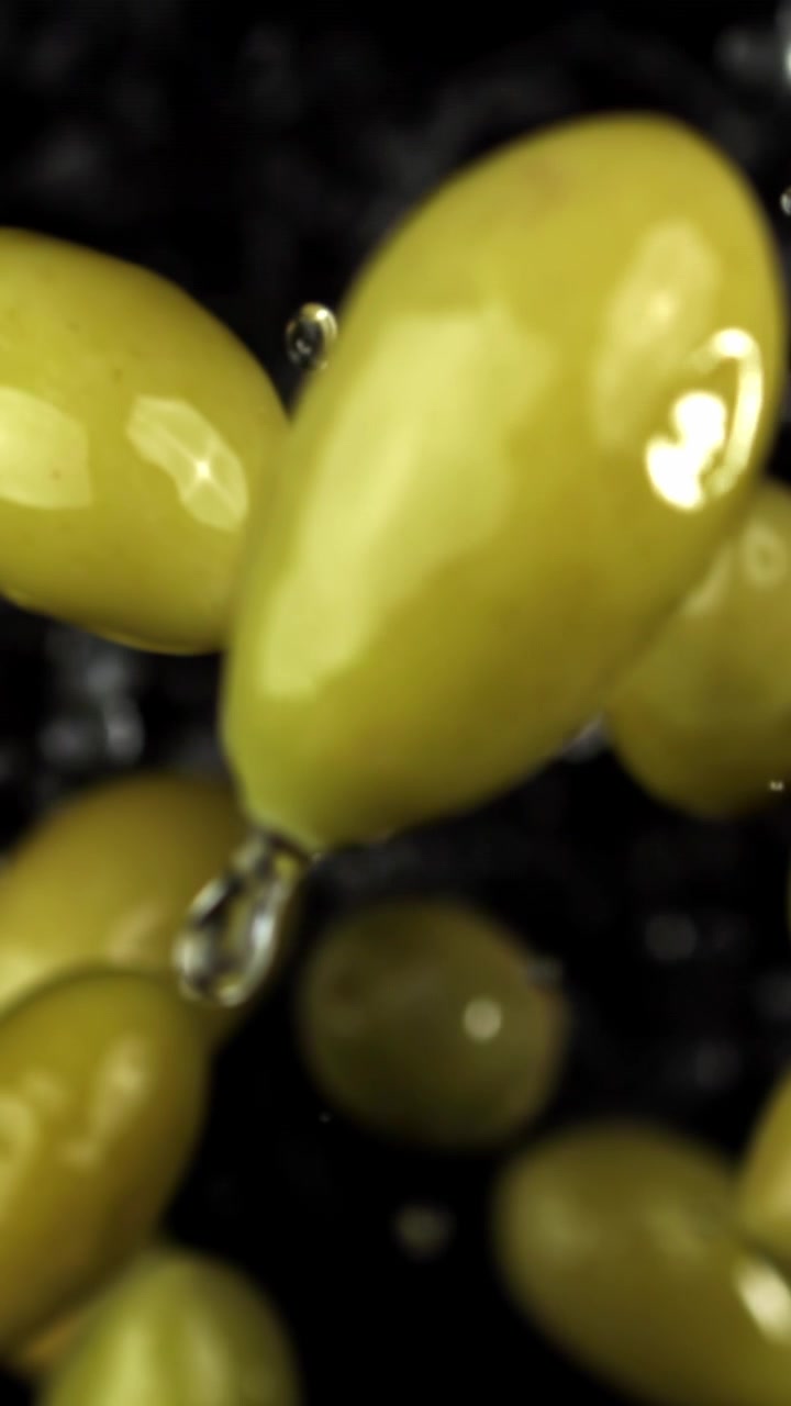 Olive verdi che galleggiano nell'acqua con goccioline su sfondo scuro