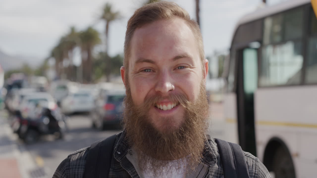 retrato de un hombre hipster barbudo riendo feliz mirando a la cámara disfrutando de las vacaciones de estilo de vida de verano en la soleada ciudad urbana frente a la playa