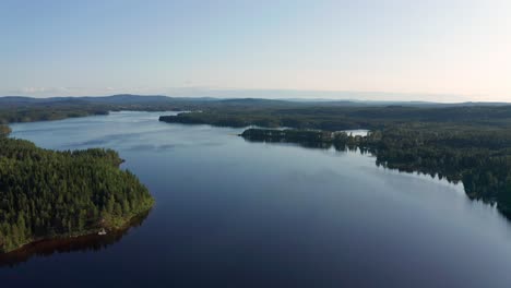 Drone-shot-of-crystal-clear-lake-in-Sweden-inland-surrounded-by-deep-forest-landscape