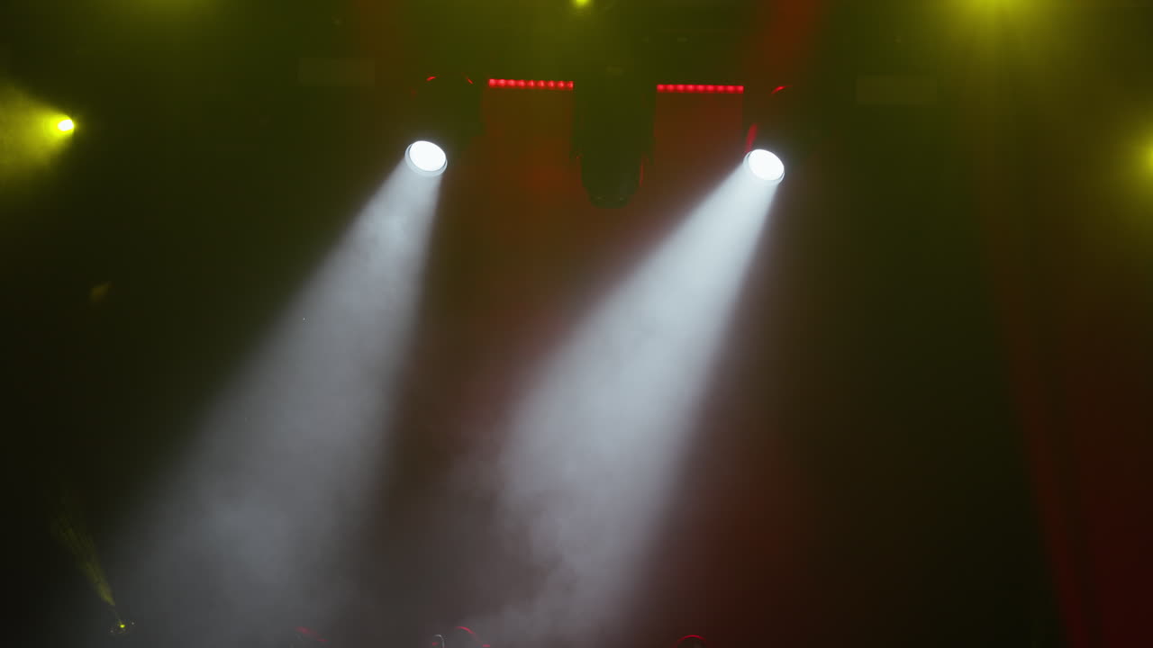 Dynamic Stage Lights Illuminating Smoke with Yellow and White Beams