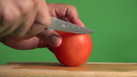 hands slicing through a tomado with a knife on a chroma background