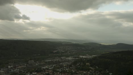 a lush valley with rays of sunlight piercing through stormy clouds, highlighting a small town, aerial view