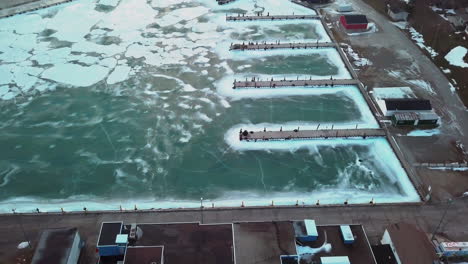 boats sit in the frozen water in lake erie along the coastline of a small canadian town