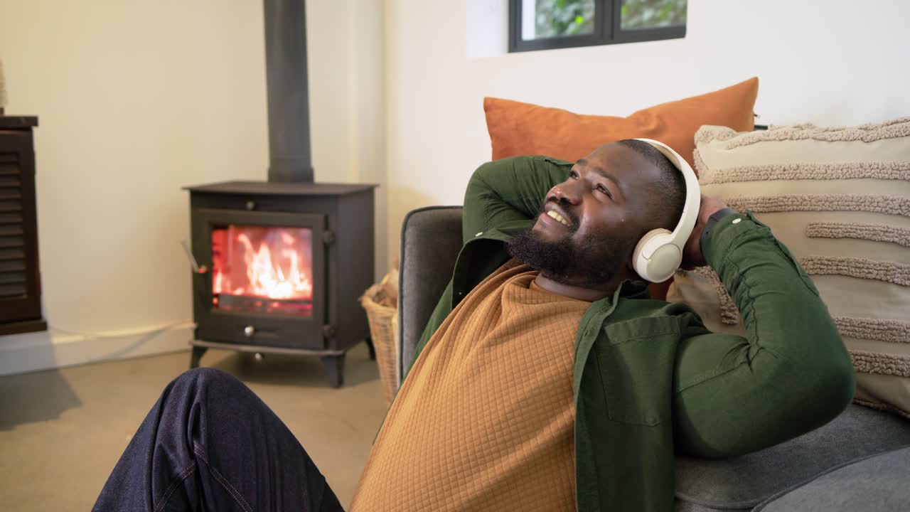 After notification African American man scrolling phone on floor at home wearing headphones to rest