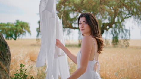 sensual lady hanging laundry at meadow closeup. romantic woman looking at camera