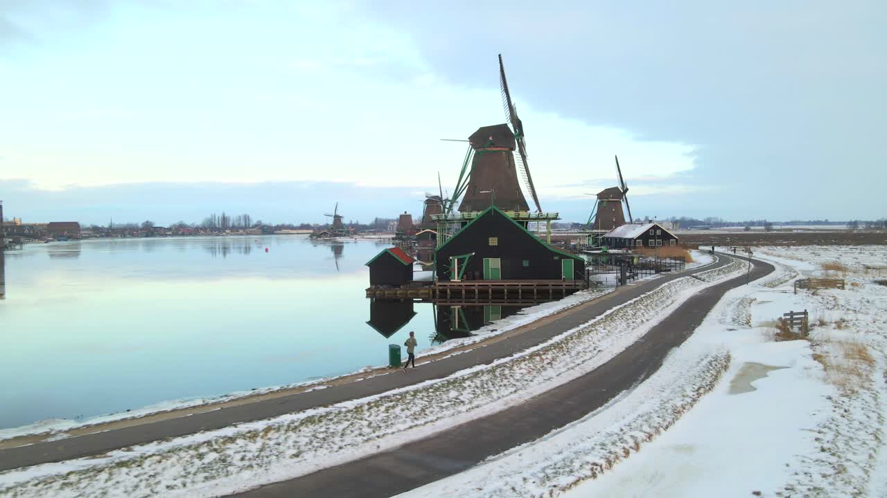 Winterliche Windmühlen und Wasserwege mit laufendem Mann, von oben gesehen, Niederlande
