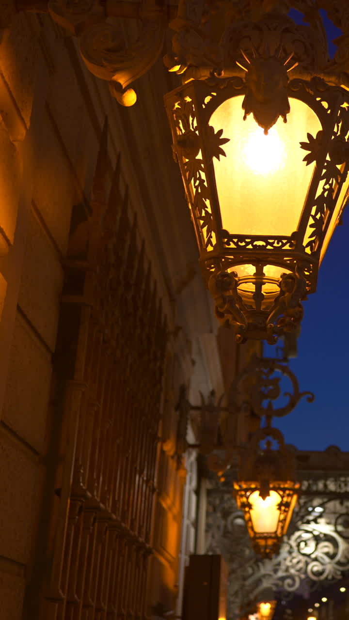 Close up of illuminated street lamps on a building in Nice, France in the evening. Vertical