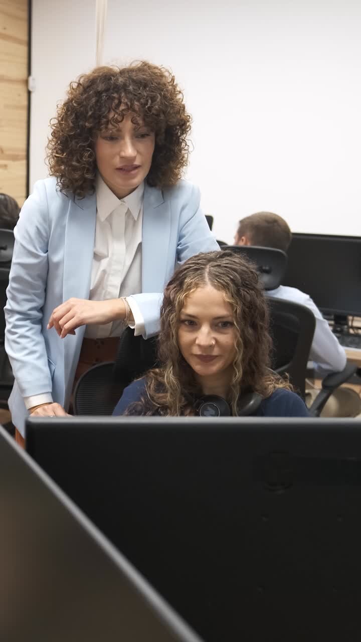 Manager explaining task to employee working on computer. Vertical footage