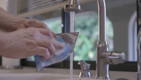 a caucasian male is cleaning a spatula in a home kitchen