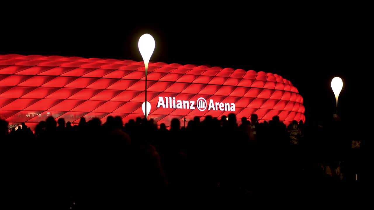 Illuminated arena of german football club FC Bayern München. Red light of Allianz Arena with silhouette of fans walking to see the match.