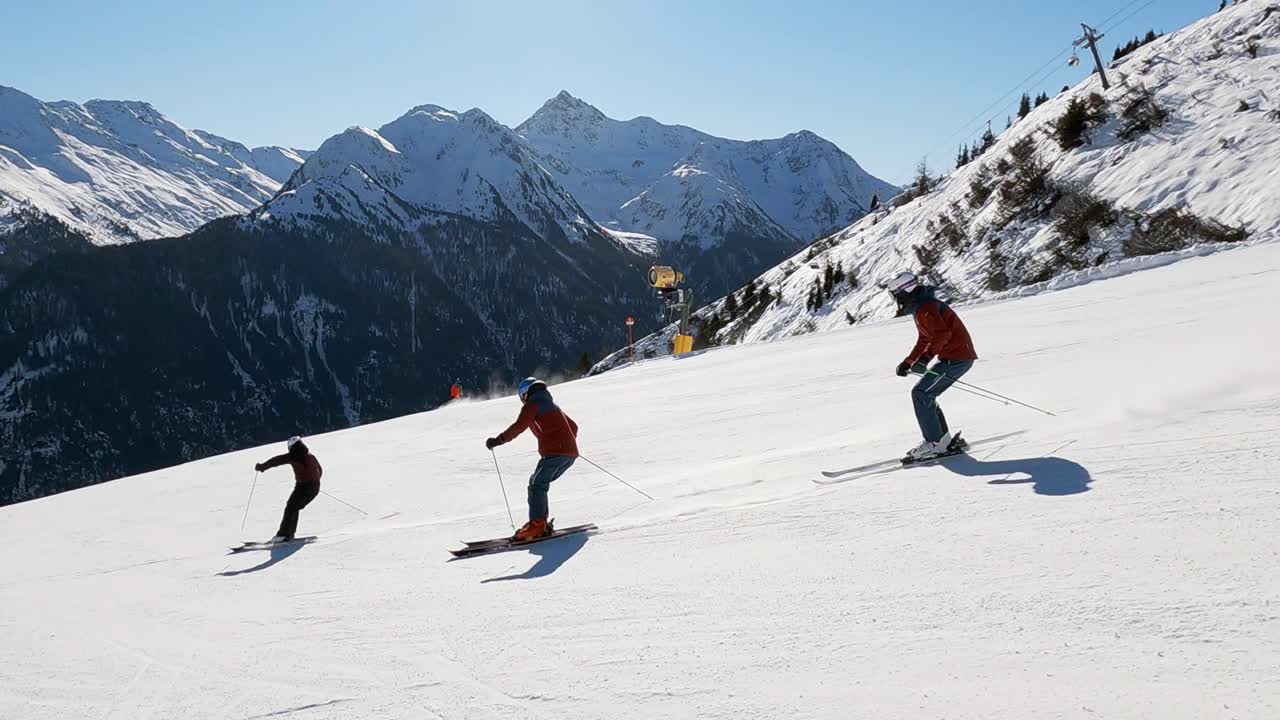 Three skiers show beautiful ski turns on a ski slope with a perfect mountain view. Three skiers image video syncron skiing, beautiful mountain view, alps,tirol, skiing.