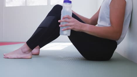 mujer caucásica bebiendo agua después del entrenamiento