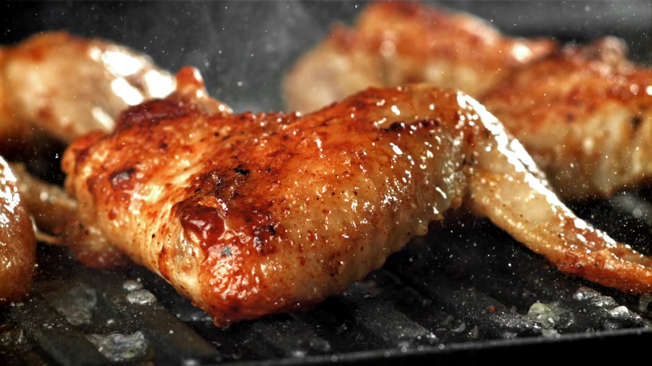 Primo piano di un'ala di pollo dorata che griglia sulla brace