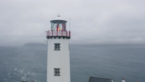 Aerial-close-up-of-lighthouses-beam-of-light-coming-from-its-lens-as-its-emitting-lamp-shines-bright