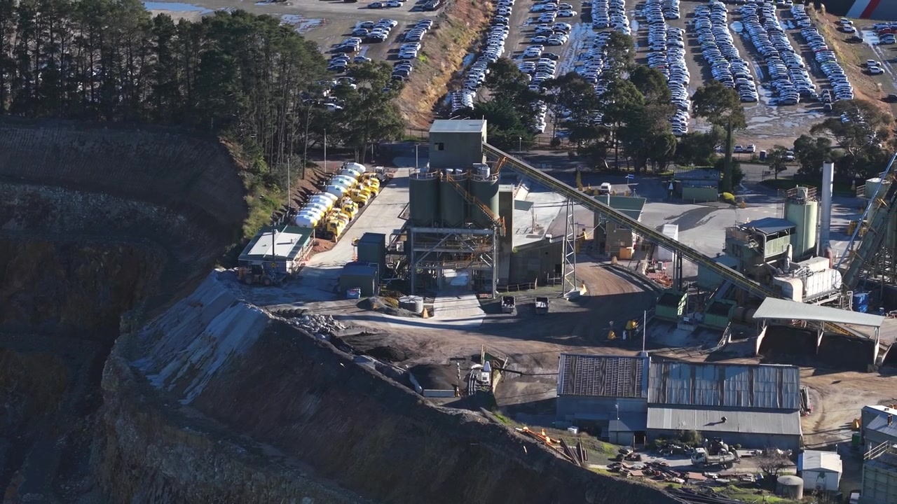 Cinematic aerial footage of Montrose Quarry near Melbourne, featuring rugged quarry cliffs, heavy equipment, conveyor systems, and a sprawling parking lot in clear daylight for industrial use.