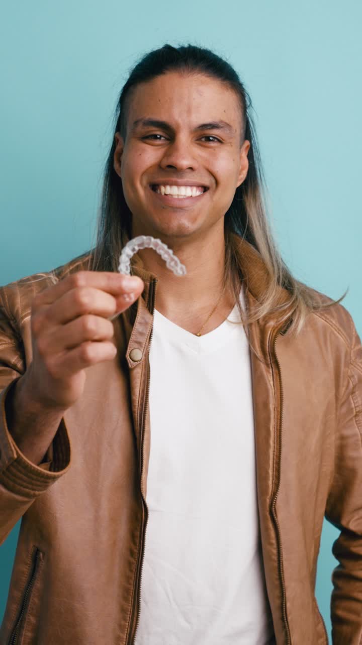 Smiling Man Holding a Clear Dental Aligner