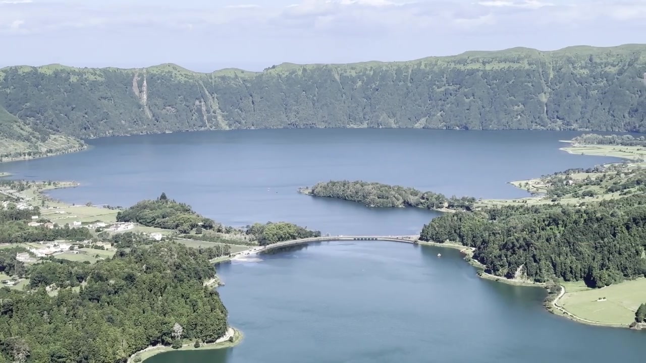 Azorlar, São Miguel Adası'ndaki Sete Cidades'ın panoramik görüntüsü, çekim sağa doğru kaydırılırken güneşli bir günde canlı gölleri gösteriyor