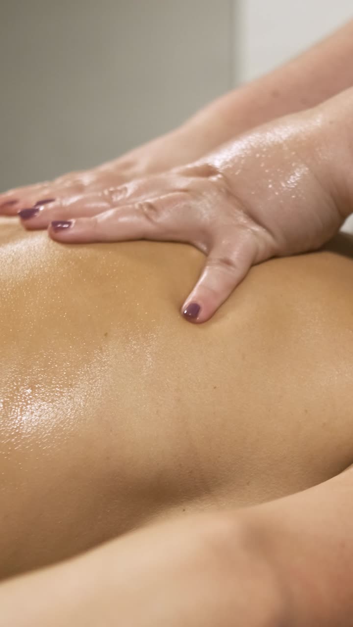 Masseuse performing relaxing back massage. Vertical