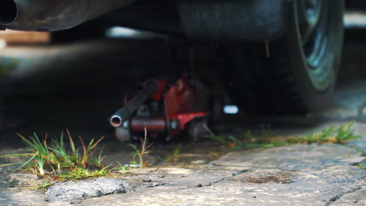 Slow motion - A man put a jack under the car for the process of changing tires