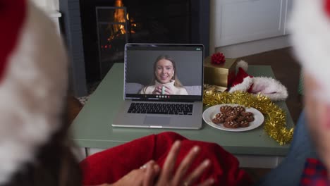 Caucasian-couple-on-video-call-on-laptop-with-female-friend-at-christmas-time
