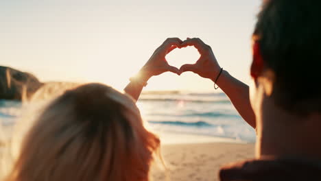 corazón, manos y pareja zoom en una playa con amor