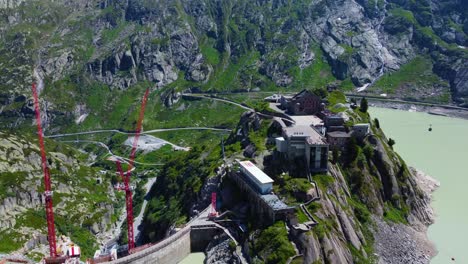 Aerial-drone-zoom-in-shot-over-Hotel-Grimsel-Hospiz-along-Grimsel-Pass,-Swiss-Mountain-in-Switzerland-on-a-sunny-day