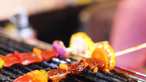close-up of vibrant skewers with vegetables and meat grilling on an open flame.